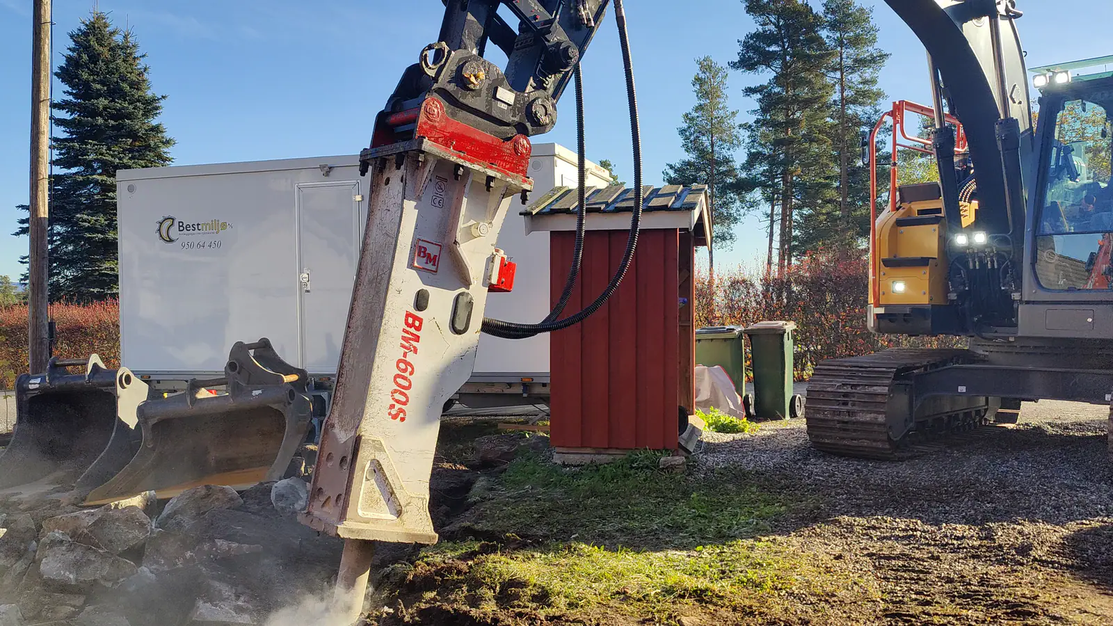 Gravemaskin på tomt med pigging med stor maskin